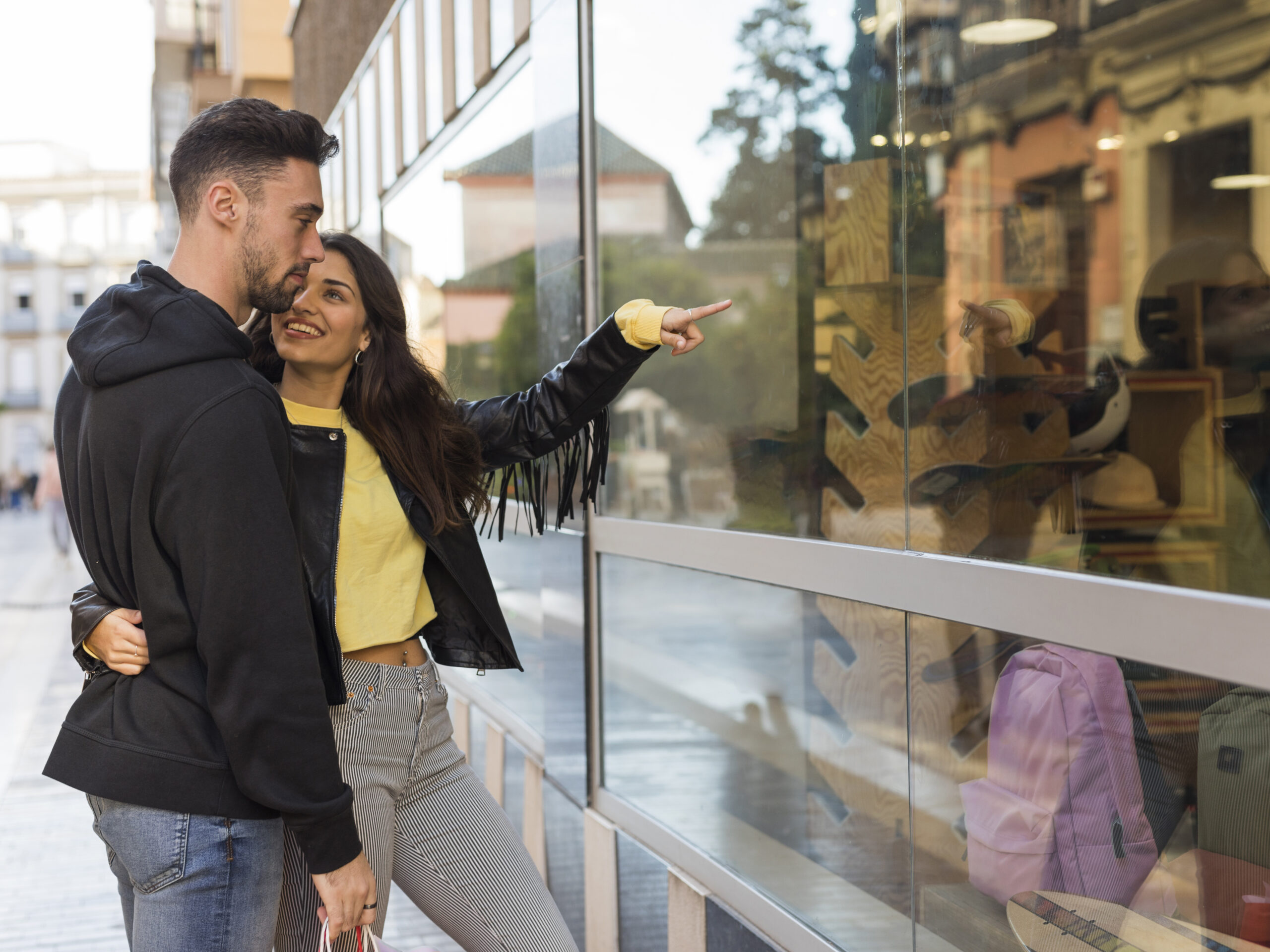 happy-woman-hugging-showing-shop-window-young-man